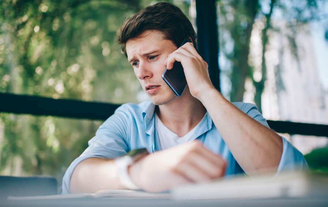 A young man who is upset on a cell phone seeking mental health support